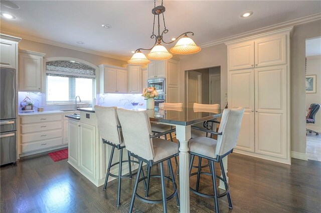 309 E 126th St, Kansas City, MO 64145 - kitchen featuring stainless steel appliances, a kitchen island, white cabinetry, dark wood-style floors, and crown molding