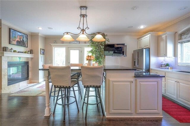 309 E 126th St, Kansas City, MO 64145 - kitchen featuring stainless steel fridge, a center island, white cabinets, ornamental molding, and a breakfast bar area