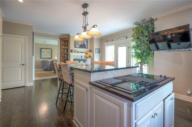 309 E 126th St, Kansas City, MO 64145 - kitchen with black electric cooktop, a breakfast bar, dark countertops, white cabinetry, and ornamental molding