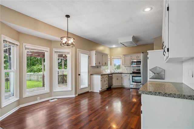 13701 W 149th St, Olathe, KS 66062 - kitchen featuring appliances with stainless steel finishes, dark wood-style floors, a textured ceiling, backsplash, and pendant lighting