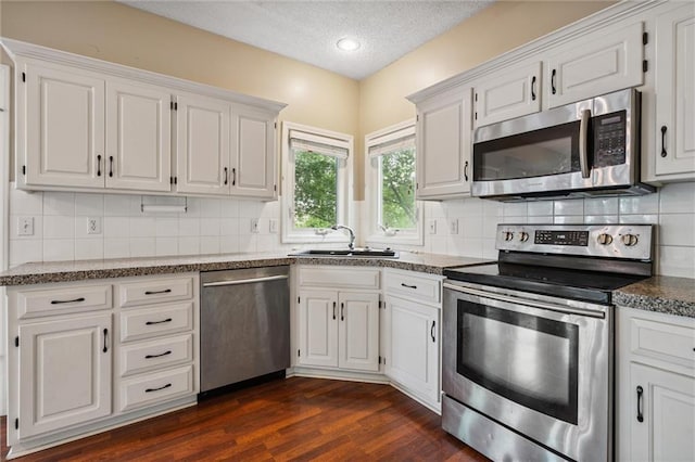 13701 W 149th St, Olathe, KS 66062 - kitchen featuring stainless steel appliances, dark wood finished floors, white cabinets, a textured ceiling, and decorative backsplash