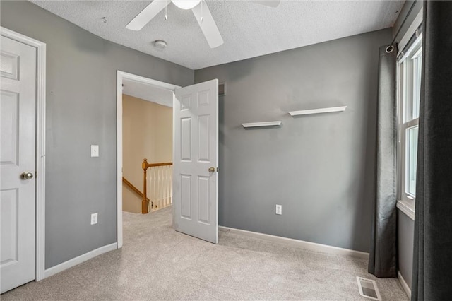 13701 W 149th St, Olathe, KS 66062 - unfurnished bedroom with multiple windows, carpet flooring, a textured ceiling, and ceiling fan