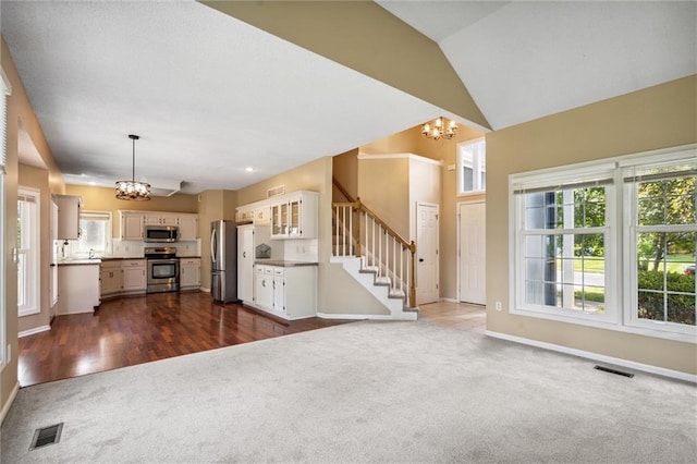 13701 W 149th St, Olathe, KS 66062 - unfurnished living room featuring a chandelier, dark carpet, stairway, plenty of natural light, and lofted ceiling