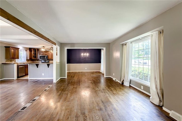 4430 E 107th Ter, Kansas City, MO 64137 - unfurnished living room with dark wood-style floors and a chandelier