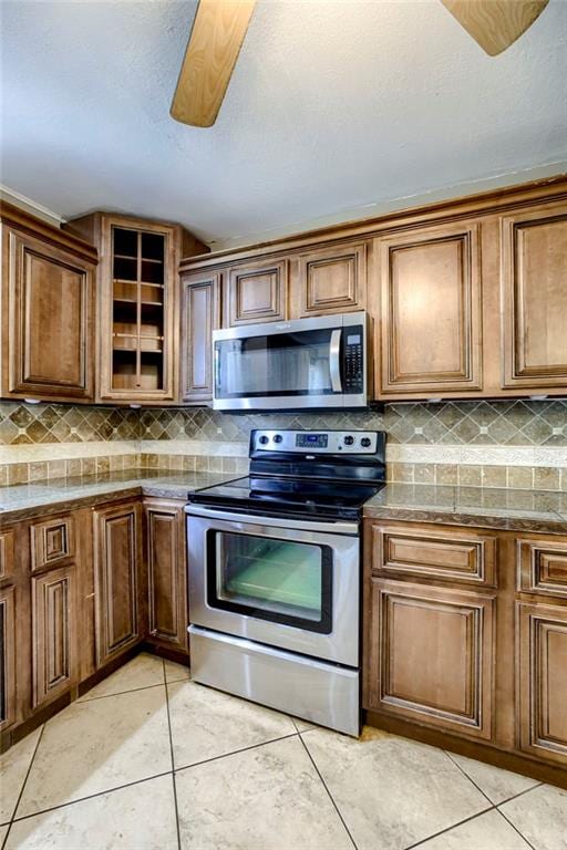 4430 E 107th Ter, Kansas City, MO 64137 - kitchen featuring appliances with stainless steel finishes, light tile patterned flooring, and decorative backsplash