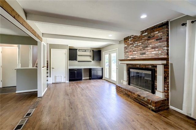 4430 E 107th Ter, Kansas City, MO 64137 - unfurnished living room with beam ceiling, a brick fireplace, and wood finished floors
