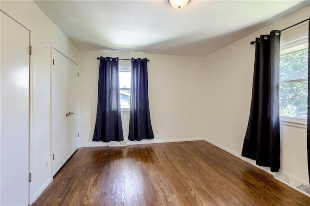 4430 E 107th Ter, Kansas City, MO 64137 - unfurnished bedroom featuring multiple windows and wood-type flooring