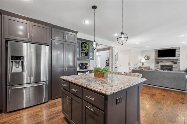 1220 Kingsland Cir, Raymore, MO 64083 - kitchen featuring stainless steel fridge with ice dispenser, a fireplace, recessed lighting, light stone countertops, and wood finished floors
