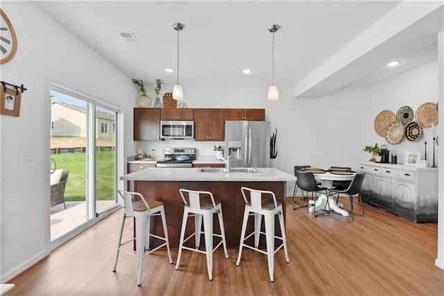 27104 E Cedar Grove Dr, Lees Summit, MO 64086 - kitchen with appliances with stainless steel finishes, light wood-style flooring, a sink, a breakfast bar, and a kitchen island with sink