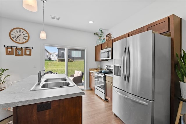 27104 E Cedar Grove Dr, Lees Summit, MO 64086 - kitchen with appliances with stainless steel finishes, a sink, decorative light fixtures, light wood finished floors, and light countertops