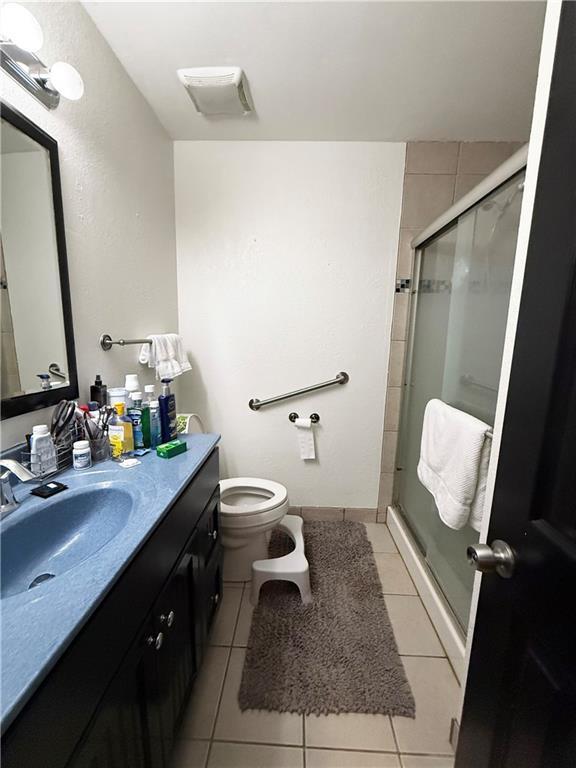 6521 W 49th St, Mission, KS 66202 - full bathroom featuring vanity, a stall shower, toilet, and tile patterned flooring