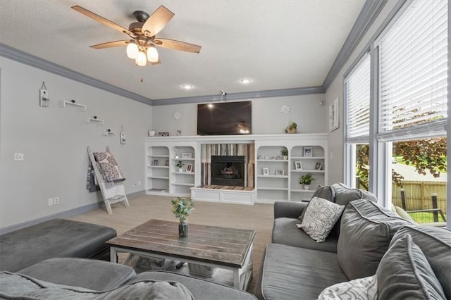 14105 W 115th St, Olathe, KS 66062 - living room with a tiled fireplace, ornamental molding, a textured ceiling, ceiling fan, and light colored carpet