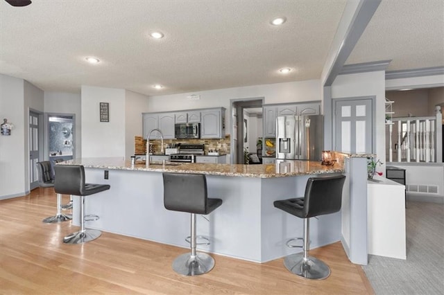 14105 W 115th St, Olathe, KS 66062 - kitchen with appliances with stainless steel finishes, a textured ceiling, gray cabinets, a kitchen breakfast bar, and a sink