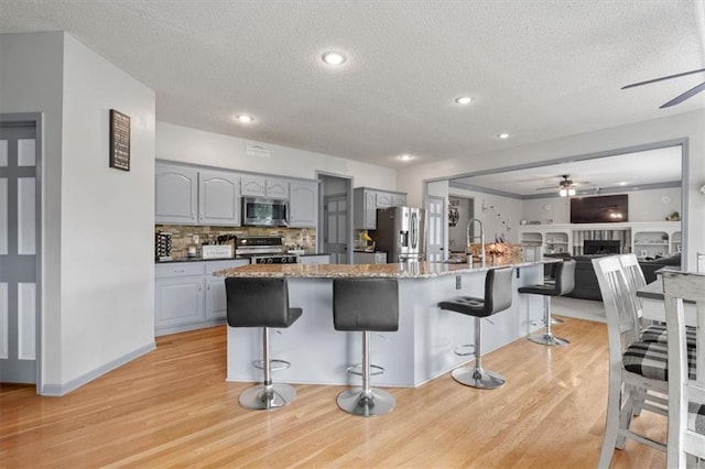 14105 W 115th St, Olathe, KS 66062 - kitchen with stainless steel appliances, ceiling fan, gray cabinetry, a textured ceiling, and light wood-style flooring