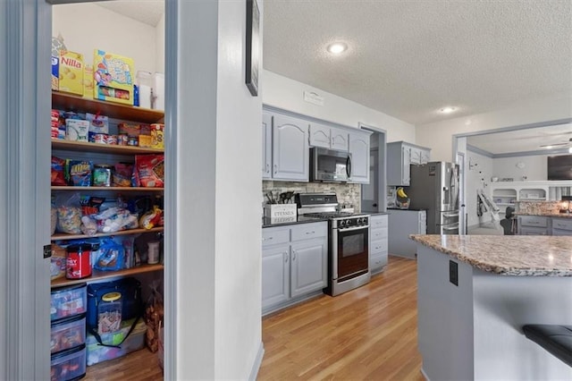 14105 W 115th St, Olathe, KS 66062 - kitchen featuring stainless steel appliances, a textured ceiling, gray cabinetry, light wood-type flooring, and tasteful backsplash