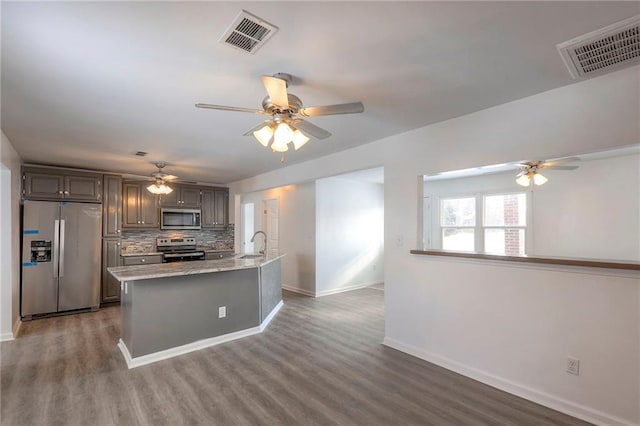 1129 US Highway 50, Centerview, MO 64019 - kitchen with stainless steel appliances, ceiling fan, tasteful backsplash, wood finished floors, and light stone counters