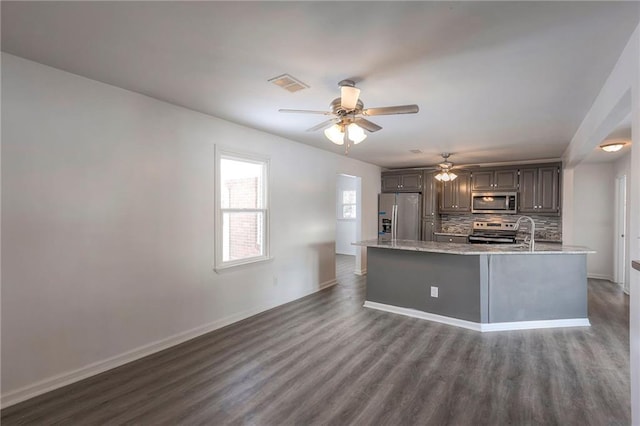 1129 US Highway 50, Centerview, MO 64019 - kitchen featuring appliances with stainless steel finishes, dark wood-style floors, decorative backsplash, and a ceiling fan