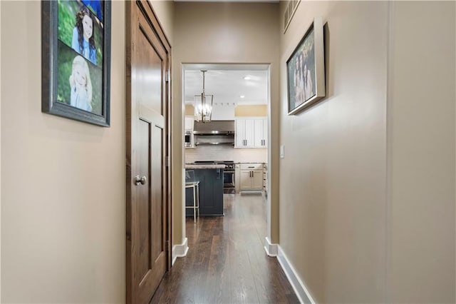 20711 Benson St, Bucyrus, KS 66013 - hall featuring dark wood-type flooring and a chandelier