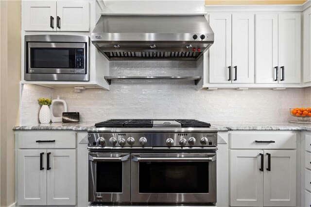20711 Benson St, Bucyrus, KS 66013 - kitchen with appliances with stainless steel finishes, exhaust hood, white cabinets, light stone countertops, and backsplash