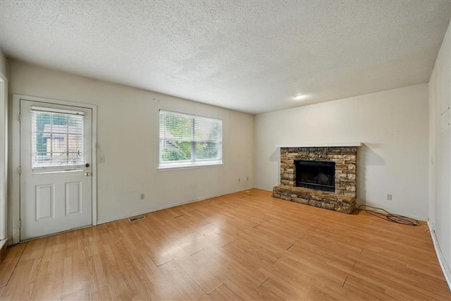 11431 Reeder St, Overland Park, KS 66210 - unfurnished living room with light wood-style flooring, a fireplace, and a textured ceiling