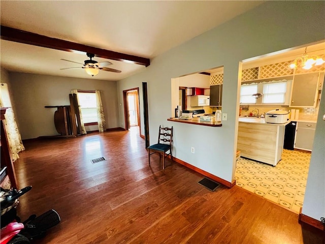 107 W 23rd St, Higginsville, MO 64037 - kitchen with wood finished floors, beam ceiling, white microwave, ceiling fan, and light countertops