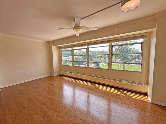 333 W Meyer Blvd Unit 414, Kansas City, MO 64113 - spare room with baseboard heating, ceiling fan, baseboards, ornamental molding, and wood finished floors