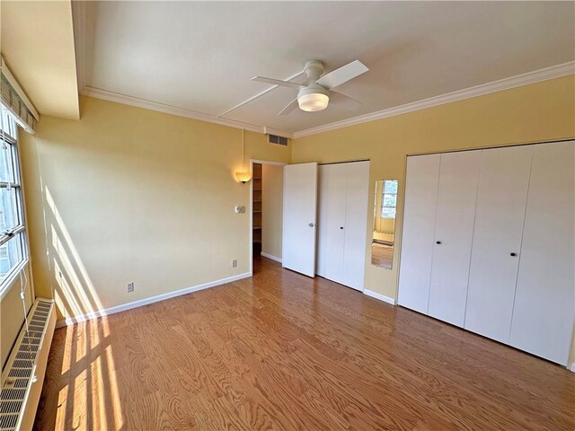 333 W Meyer Blvd Unit 414, Kansas City, MO 64113 - unfurnished bedroom featuring two closets, crown molding, multiple windows, wood finished floors, and baseboards