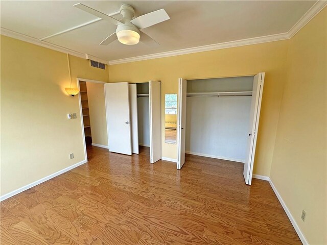 333 W Meyer Blvd Unit 414, Kansas City, MO 64113 - unfurnished bedroom with multiple closets, ornamental molding, wood finished floors, baseboards, and ceiling fan