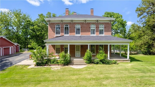5322 SE Riverside Ter, Saint Joseph, MO 64507 - italianate home featuring a porch, a chimney, brick siding, a front yard, and an outdoor structure
