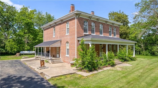 5322 SE Riverside Ter, Saint Joseph, MO 64507 - rear view of house with a chimney, a porch, brick siding, and a yard