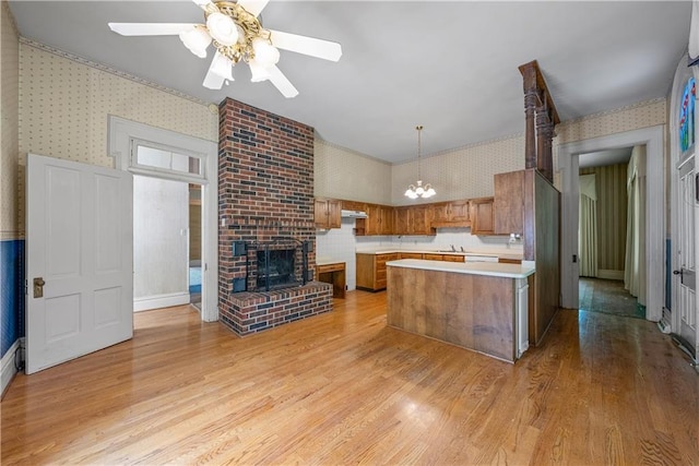 5322 SE Riverside Ter, Saint Joseph, MO 64507 - kitchen with wallpapered walls, brown cabinetry, light countertops, a ceiling fan, and light wood-type flooring