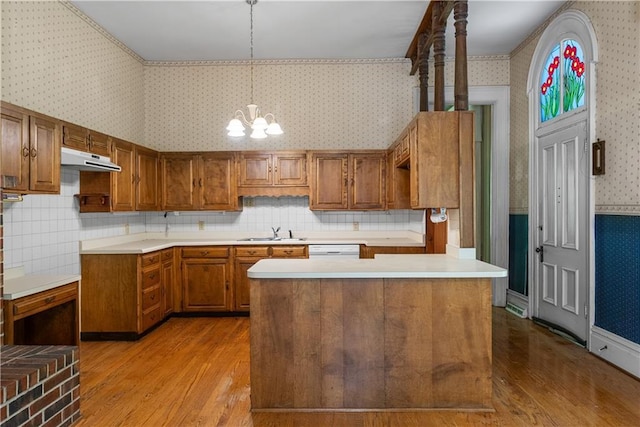 5322 SE Riverside Ter, Saint Joseph, MO 64507 - kitchen featuring wallpapered walls, a sink, brown cabinets, and wood finished floors
