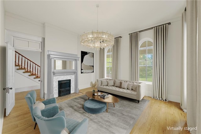 5322 SE Riverside Ter, Saint Joseph, MO 64507 - living room featuring light wood-style flooring, a chandelier, stairs, a fireplace, and ornamental molding