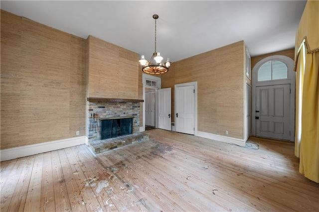 5322 SE Riverside Ter, Saint Joseph, MO 64507 - unfurnished living room featuring a chandelier, hardwood / wood-style floors, a fireplace, a towering ceiling, and baseboards