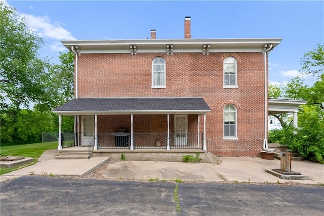 5322 SE Riverside Ter, Saint Joseph, MO 64507 - rear view of house with covered porch, brick siding, and a chimney