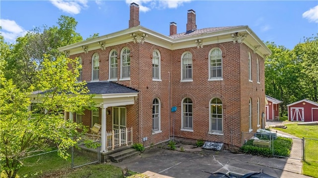 5322 SE Riverside Ter, Saint Joseph, MO 64507 - italianate home with a chimney, brick siding, a porch, and a gate