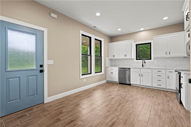 26696 235th St, Mclouth, KS 66054 - kitchen with appliances with stainless steel finishes, baseboards, light wood-style floors, decorative backsplash, and white cabinets
