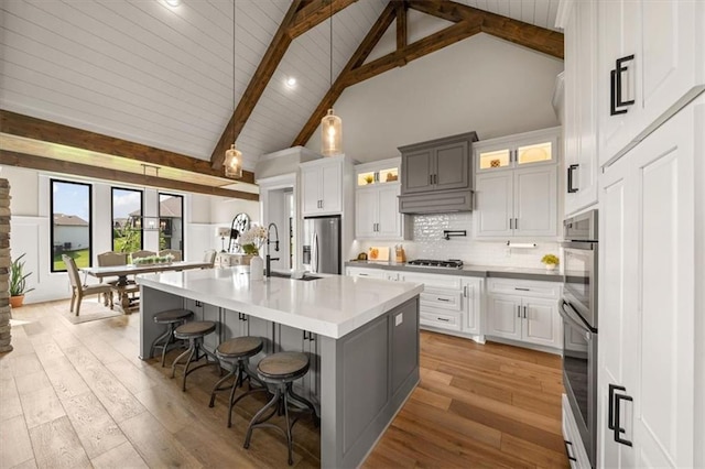 3053 NW Thoreau Ln, Lees Summit, MO 64081 - kitchen with appliances with stainless steel finishes, high vaulted ceiling, a kitchen breakfast bar, backsplash, and light wood finished floors