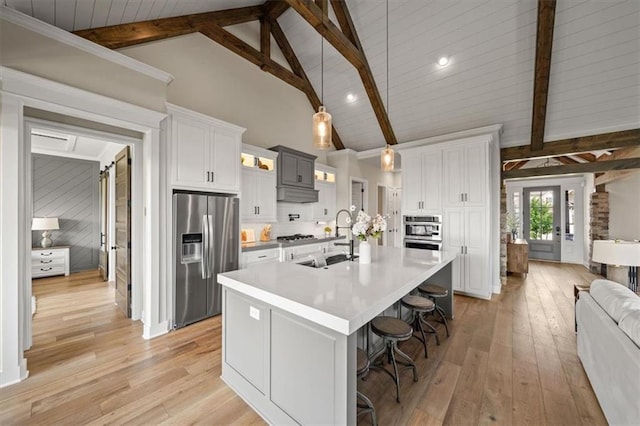 3053 NW Thoreau Ln, Lees Summit, MO 64081 - kitchen with appliances with stainless steel finishes, light wood-type flooring, light countertops, a kitchen bar, and high vaulted ceiling