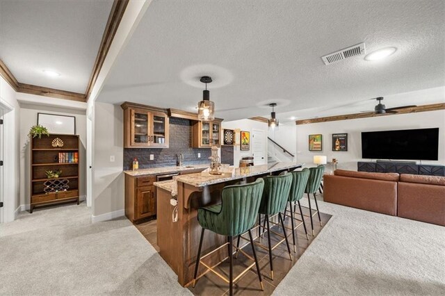 3053 NW Thoreau Ln, Lees Summit, MO 64081 - kitchen featuring a breakfast bar, brown cabinets, light colored carpet, a textured ceiling, and recessed lighting