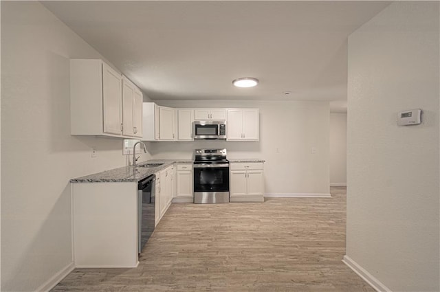 3874 E 63rd St, Kansas City, MO 64130 - kitchen featuring appliances with stainless steel finishes, light wood-style floors, white cabinetry, and light stone countertops