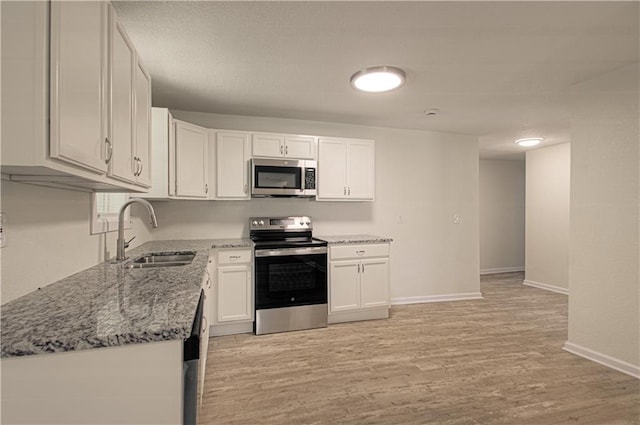 3874 E 63rd St, Kansas City, MO 64130 - kitchen with appliances with stainless steel finishes, light stone countertops, light wood-style flooring, and white cabinets