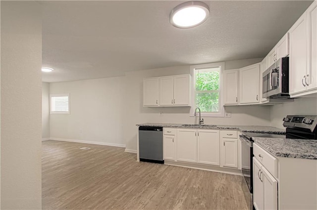 3874 E 63rd St, Kansas City, MO 64130 - kitchen with stainless steel appliances, light wood finished floors, white cabinets, light stone countertops, and a textured ceiling