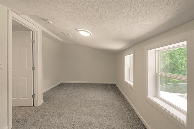 3874 E 63rd St, Kansas City, MO 64130 - spare room featuring carpet, healthy amount of natural light, a textured ceiling, lofted ceiling, and a smoke detector