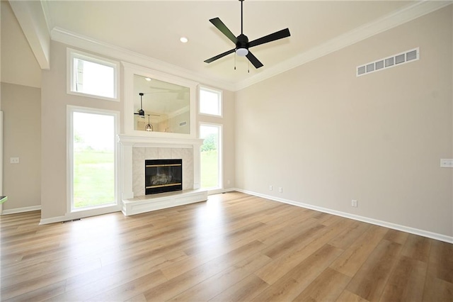18 Timber Creek Cir, Platte City, MO 64079 - unfurnished living room with crown molding, light wood-style flooring, ceiling fan, a tiled fireplace, and a towering ceiling