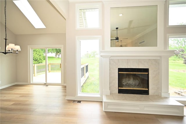 18 Timber Creek Cir, Platte City, MO 64079 - unfurnished living room featuring a fireplace, wood finished floors, a chandelier, ceiling fan, and a skylight