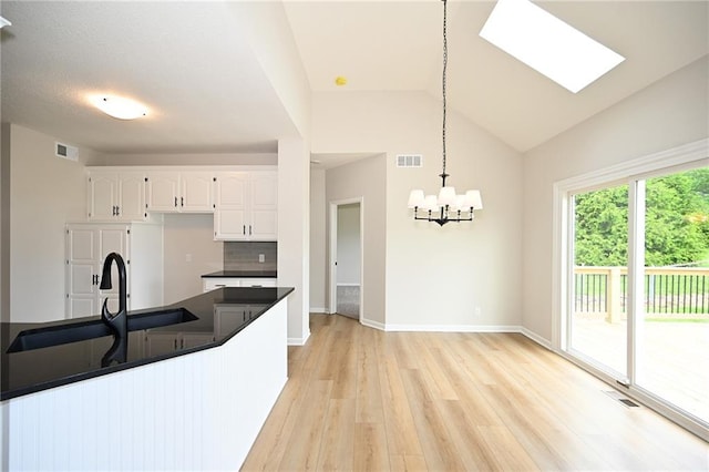 18 Timber Creek Cir, Platte City, MO 64079 - kitchen featuring dark countertops, light wood-style flooring, a chandelier, white cabinets, and vaulted ceiling