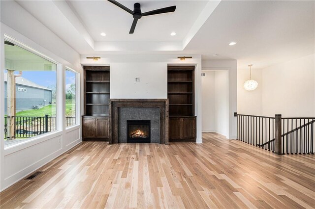 12445 Empress St, Platte City, MO 64079 - unfurnished living room with wood finished floors, a ceiling fan, a lit fireplace, a raised ceiling, and baseboards
