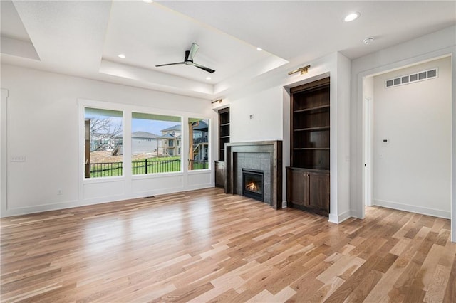 12445 Empress St, Platte City, MO 64079 - unfurnished living room with a raised ceiling, light wood-type flooring, a lit fireplace, ceiling fan, and recessed lighting