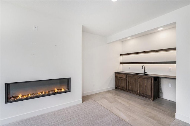 12445 Empress St, Platte City, MO 64079 - bar area featuring a sink, a glass covered fireplace, recessed lighting, baseboards, and light wood finished floors